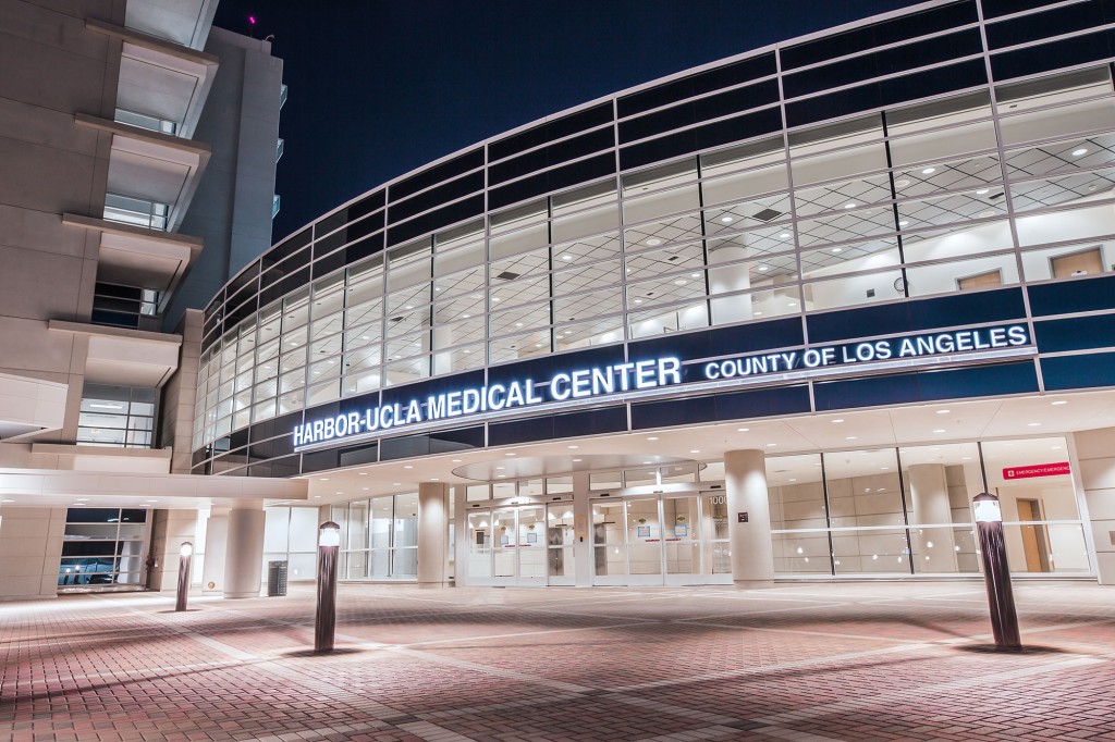 The image shows the entrance of Harbor-UCLA Medical Center at night, featuring modern architecture and illuminated signage.